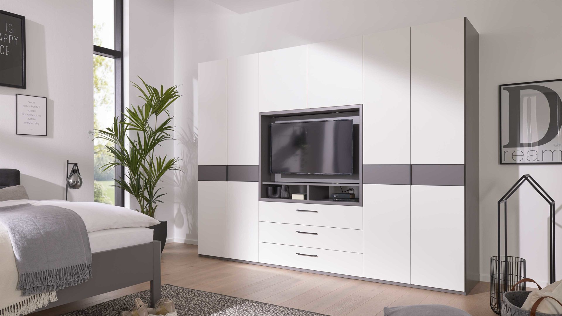 Kleiderschrank Interliving aus Holz in Grau Interliving Kleiderschrank Serie 1207 – Kleiderschrank mit TV-Nische Weiß & Manhattan – sechs Türen, zwei Schubladen, Breite ca. 300 cm