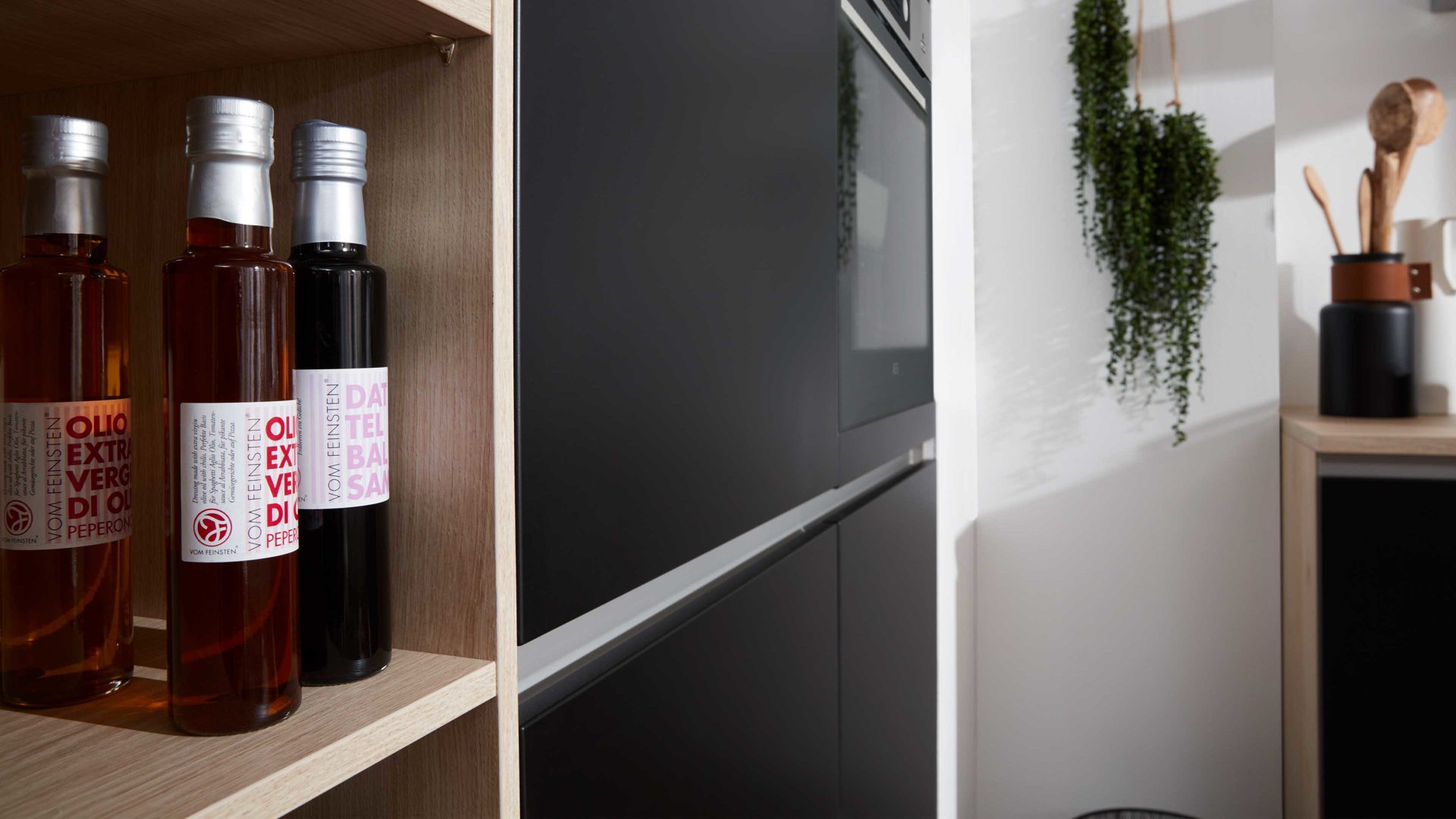 Einbauküche Interliving aus Holz in Schwarz Interliving Küche Serie 3024 mit AEG-Einbaugeräten Mattschwarz & Asteiche natur – zweizeilig