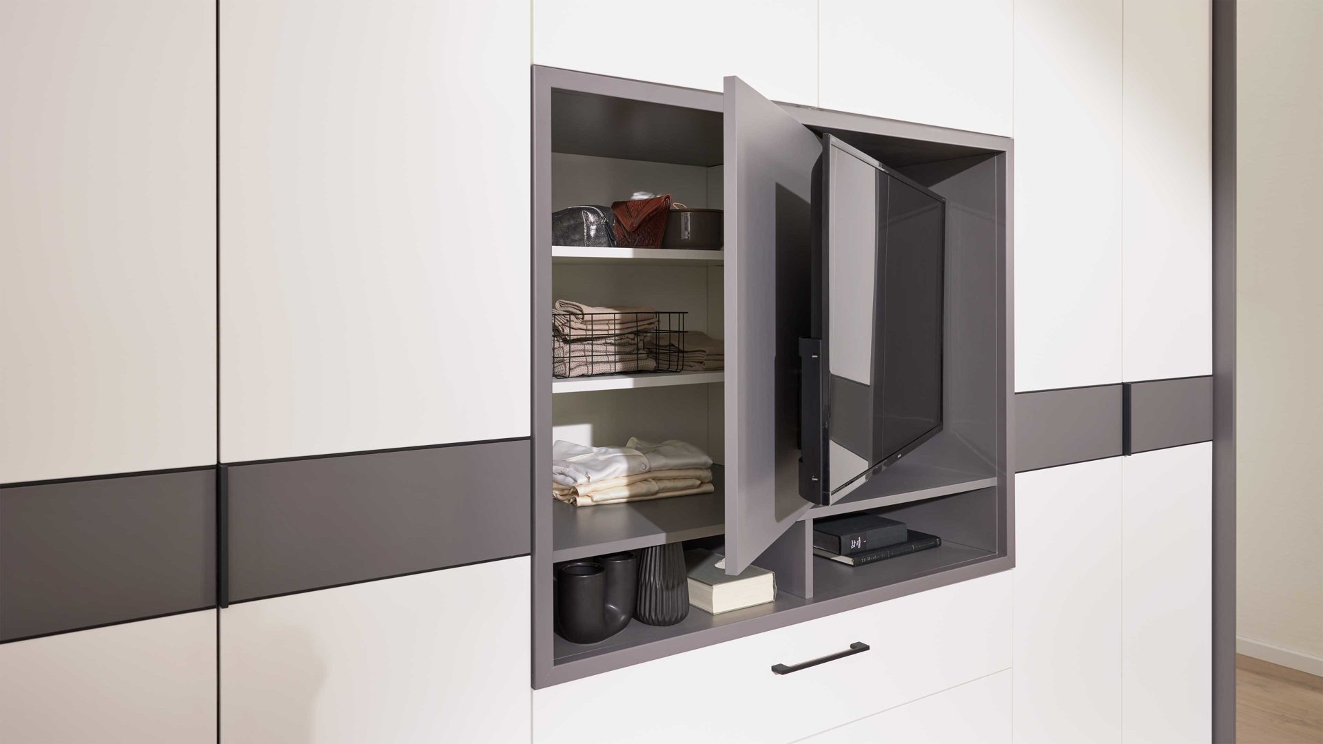 Kleiderschrank Interliving aus Holz in Grau Interliving Kleiderschrank Serie 1207 – Kleiderschrank mit TV-Nische Weiß & Manhattan – sechs Türen, zwei Schubladen, Breite ca. 300 cm